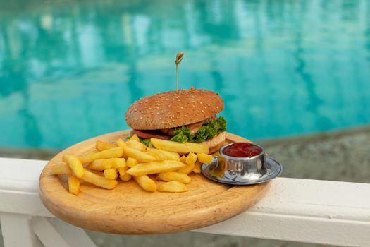 tasty hamburger, appetizing french fries and ketchup. concept of relaxing and eating by the sea on a bright, hot and sunny day on the beach. soft focus. copy space