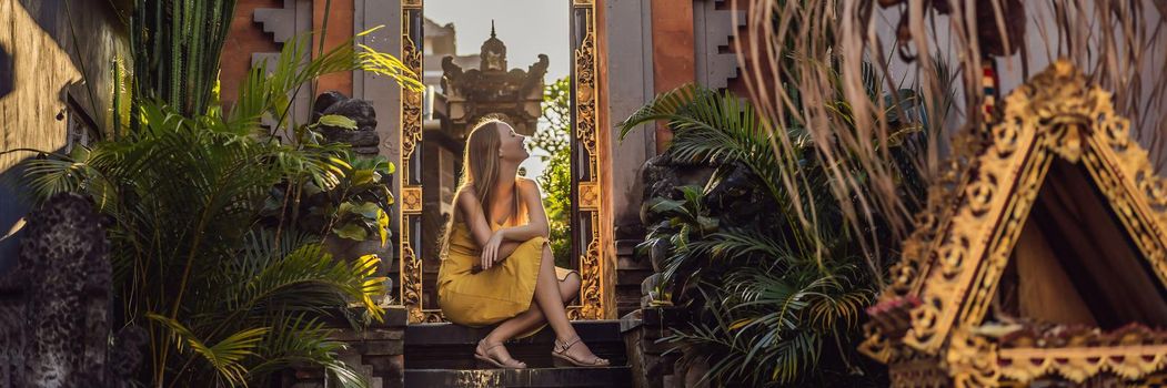 Young woman tourist on the background of Balinese doors. Bali Travel Concept. BANNER, LONG FORMAT