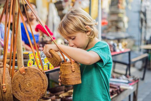 Boy at a market in Ubud, Bali. Typical souvenir shop selling souvenirs and handicrafts of Bali at the famous Ubud Market, Indonesia. Balinese market. Souvenirs of wood and crafts of local residents.