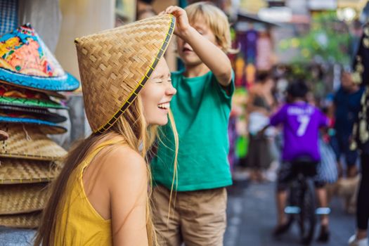 Mom and son travelers choose souvenirs in the market at Ubud in Bali, Indonesia.