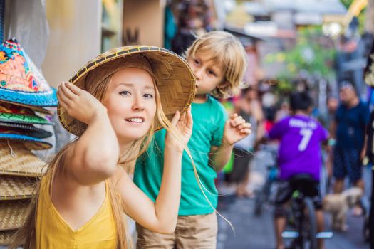 Mom and son travelers choose souvenirs in the market at Ubud in Bali, Indonesia.