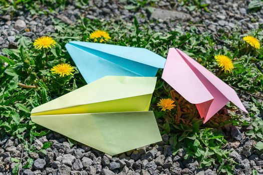 Children's multi-colored airplanes folded from paper on the grass