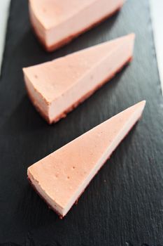 Pink pieces of cake on a black tray. High quality photo