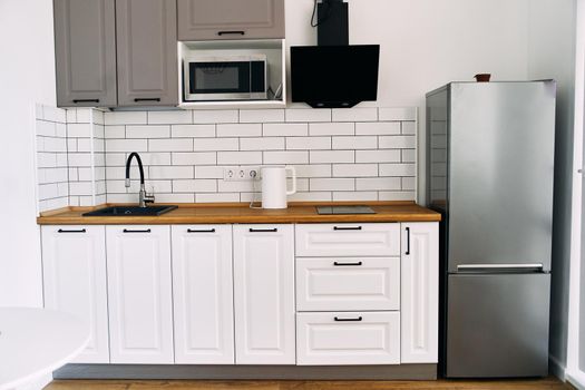 White cabinets with wooden counter of modern kitchen. High quality photo