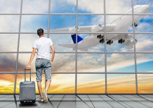 Young Asian man walking in the airport terminal with suitcase luggage. Travel lifestyle concept. High quality photo