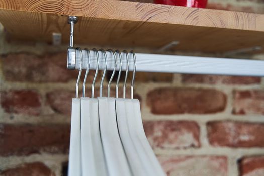 Many wooden white hangers on a rod. Store concept, sale, design, empty hanger. High quality photo