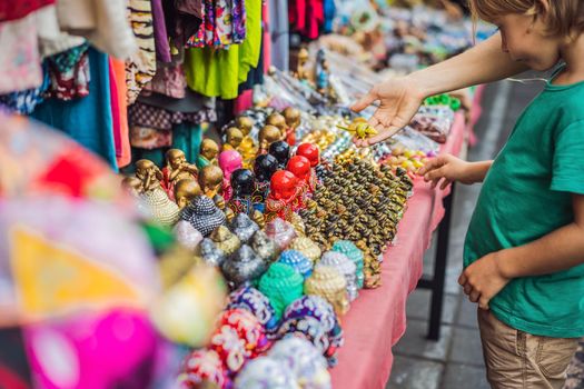 Mom and son travelers choose souvenirs in the market at Ubud in Bali, Indonesia.