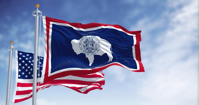 The Wyoming state flag waving along with the national flag of the United States of America. Wyoming is a state in the Mountain West subregion of the Western United States