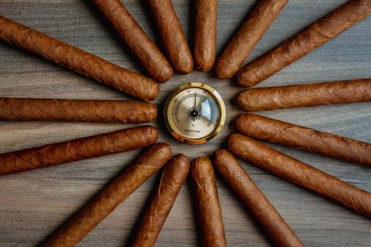 Pile of cigars with humidor hygrometer on the wooden background