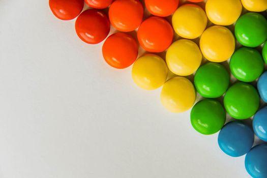Rainbow of multicolored sweet candy dragees on isolated white background. Decorative Creative composition of round candy dragees in Rainbow colors. Concept Summer. Top view. Flat lay.