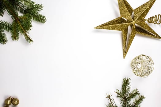 Christmas composition with green fir branches and golden decorations on a white background, copy space. Gold star.