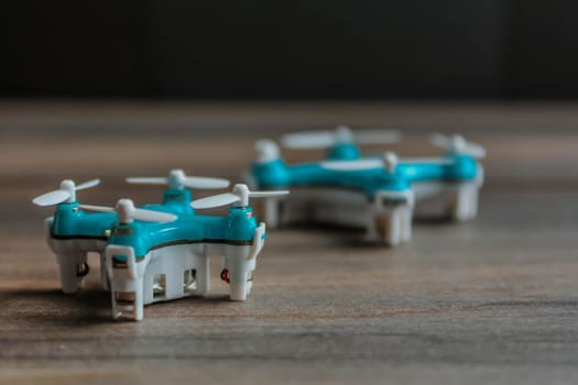 View of tiny drone on a wooden background. Small blue drone with white propellers.