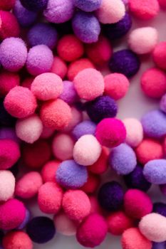 Round pink and purple fluffy balls pompoms on wooden background. Bunch of poppoms