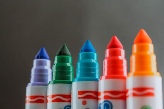 Colorful rainbow markers with blurred dark background. Side view