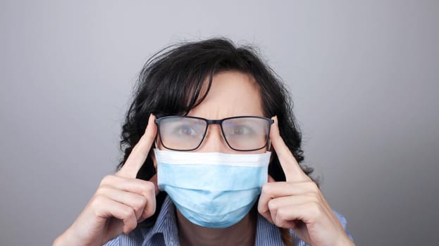 Woman wearing protection face mask against coronavirus and misted glasses. Woman in a mask looking in a mirror. Medical mask, Close up shot, Select focus, Prevention from covid19