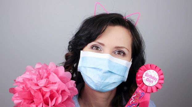 Woman wearing protection face mask against coronavirus. Woman in a mask with party supply. Happy birthday girl with cat ear headband. Medical mask, Close up shot, Select focus, Prevention from covid19