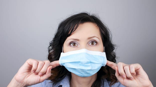 Woman wearing protection face mask against coronavirus. Woman in pulling mask away. Cannot breath. Removing face mask with fingers. Medical mask, Close up shot, Select focus, Prevention from covid19