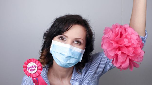 Woman wearing protection face mask against coronavirus. Woman in a mask with party supply. Birthday girl. Medical mask, Close up shot, Select focus, Prevention from covid19