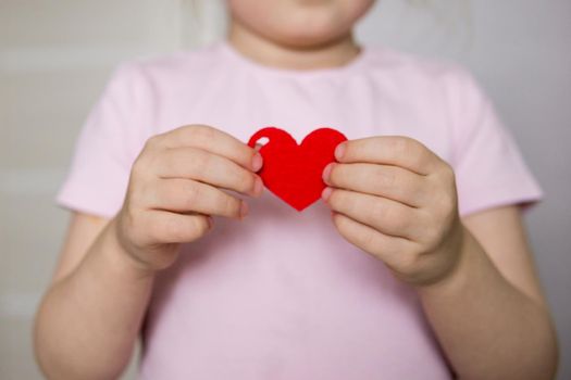 A blogger girl makes a felt craft for Valentine's Day in the shape of a heart. The concept of children's creativity and handmade.