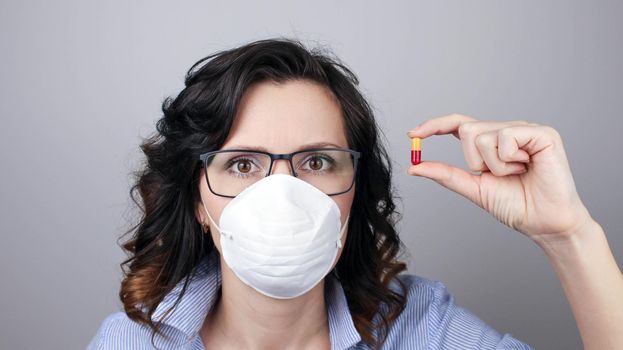 Woman wearing protection face mask against coronavirus and glasses. Woman in a mask showing medicine pill, vaccine. Medical mask, Close up shot, Select focus, Prevention from covid19