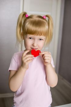 A blogger girl makes a felt craft for Valentine's Day in the shape of a heart. The concept of children's creativity and handmade.