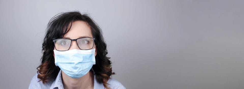 Woman wearing protection face mask against coronavirus and misted glasses. Woman in a mask looking in a mirror. Medical mask, Close up shot, Select focus, Prevention from covid19