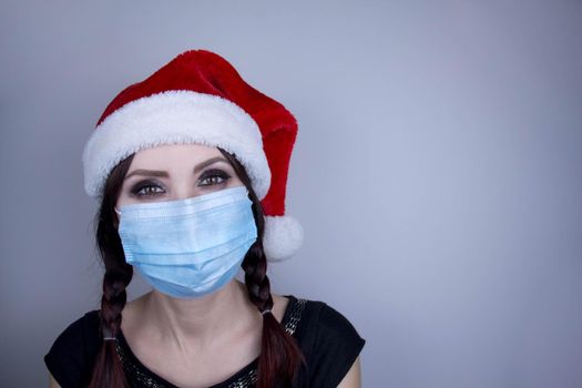 Woman wearing protection face mask against coronavirus. Woman in a mask and Christmas hat. Funny Christmas accessory. Medical mask, Close up shot, Select focus, Prevention from covid19