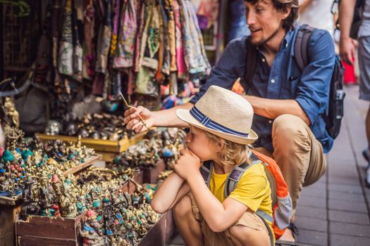 Dad and son at a market in Ubud, Bali. Typical souvenir shop selling souvenirs and handicrafts of Bali at the famous Ubud Market, Indonesia. Balinese market. Souvenirs of wood and crafts of local.