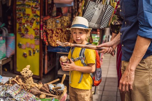 Dad and son at a market in Ubud, Bali. Typical souvenir shop selling souvenirs and handicrafts of Bali at the famous Ubud Market, Indonesia. Balinese market. Souvenirs of wood and crafts of local.