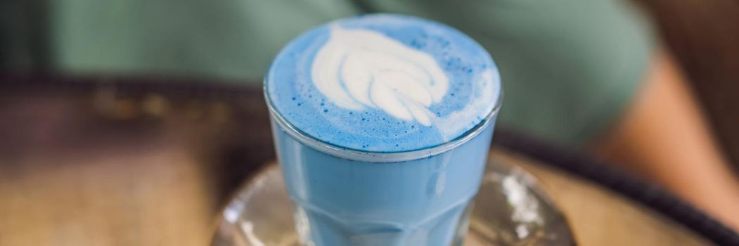 Trendy drink: Blue latte. Top view of hot butterfly pea latte or blue spirulina latte on gray textured background. Copy space for text. BANNER, LONG FORMAT