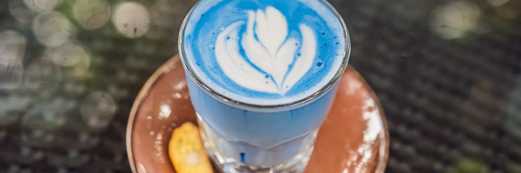 Trendy drink: Blue latte. Top view of hot butterfly pea latte or blue spirulina latte on gray textured background. Copy space for text. BANNER, LONG FORMAT