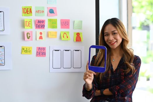 Professional web developer standing in creative office and smiling to camera.