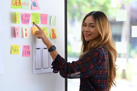 Attractive web developer planning application template layout framework for mobile phone on whiteboard.