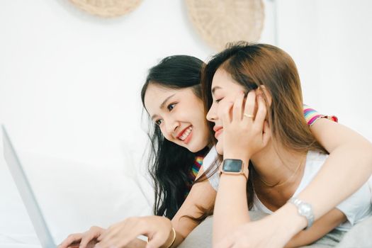 lgbtq, lgbt concept, homosexuality, portrait of two asian women posing happy together and loving each other while playing computer laptop on bed.