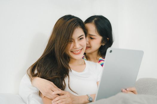 lgbtq, lgbt concept, homosexuality, portrait of two asian women posing happy together and loving each other while playing tablet on bed.