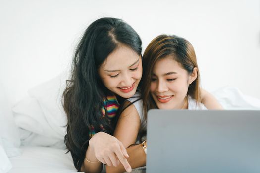 lgbtq, lgbt concept, homosexuality, portrait of two asian women posing happy together and loving each other while playing computer laptop on bed.