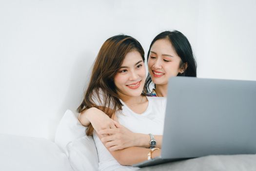 lgbtq, lgbt concept, homosexuality, portrait of two asian women posing happy together and loving each other while playing computer laptop on bed.