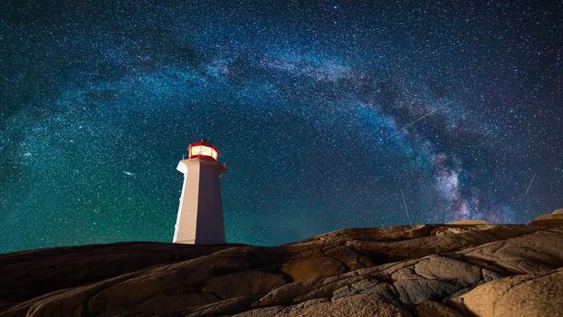 Lighthouse surrounded by rocks at night, lighthouse with lights on at night