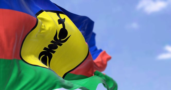 The flag of New Caledonia waving in the wind on a clear day. New Caledonia is a sui generis collectivity of overseas France in the southwest Pacific Ocean