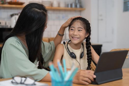 Happy mother with her young daughter enjoying in online shopping or working from home. Business from distance and virtual communication with family and friends