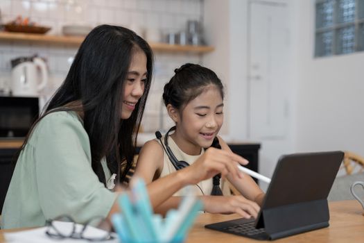 Asian young mother with computer notebook teaching kid to learn or study online at home, Homeschooling online concept.