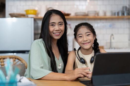 Happy asian mother with her young daughter enjoying in online shopping or working from home. Business from distance and virtual communication with family and friends.