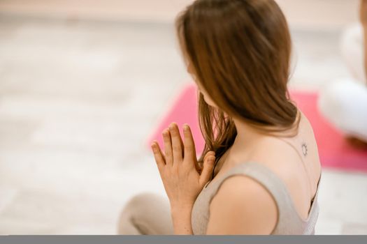 Girl does yoga. Young woman practices asanas on a beige one-ton background