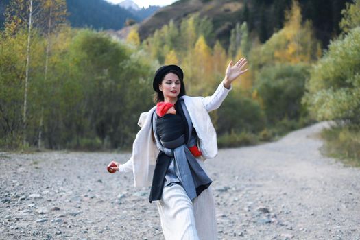 Beautiful young mother with her infant baby in sling outdoor. Mother is carrying her child and travel in autumn mountain. Active mother concept