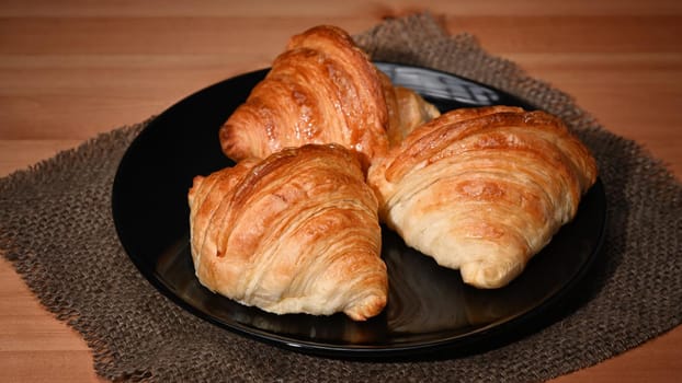 Fresh baked croissant on wooden table for homemade breakfast.