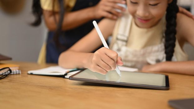 Focused asian girl using digital tablet, doing homework, studying online on web virtual class.