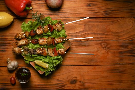 Grilled meat, vegetables and barbecue sauce on rustic wooden table. Barbecue, food, party concept.