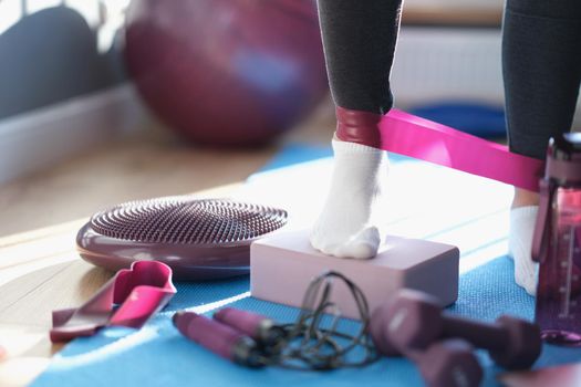 A man is doing stretching of the shins with a tape, legs close-up. Sports accessories for gymnastics, dumbbells and jump rope