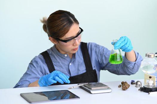 Female scientist holding a glass bowl with extracted from a marijuana plant. Concept of herbal alternative medicine, cbd oil, pharmaceutical industry.