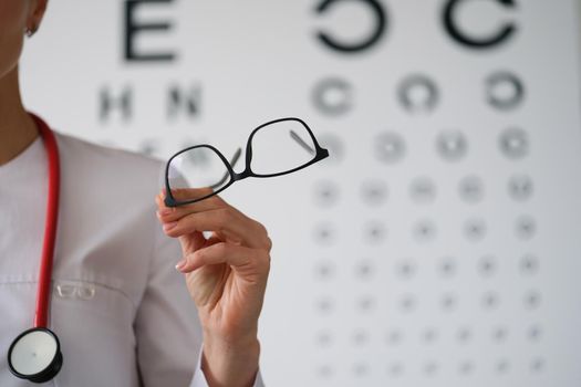 Woman doctor ophthalmologist shows glasses, close-up. Vision diagnostics, professional consultation with an eye doctor